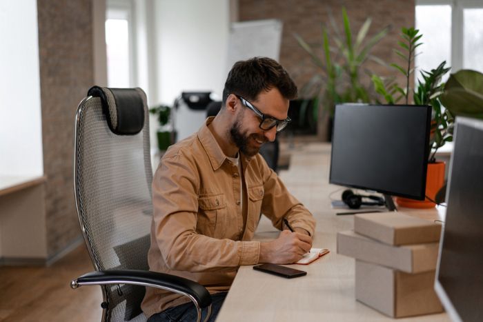 homem sentado fazendo anotações em escritório