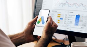 Mãos segurando um celular com o aplicativo do google ads.
