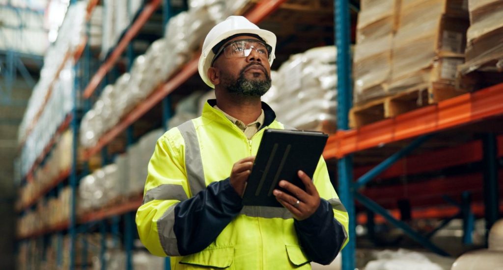 Um homem com um tablet em um estoque logístico.