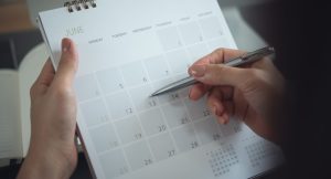 Um calendário sendo preenchido com uma caneta.