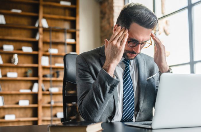 Homem com dor de cabeça por conta de rotina desorganizada.