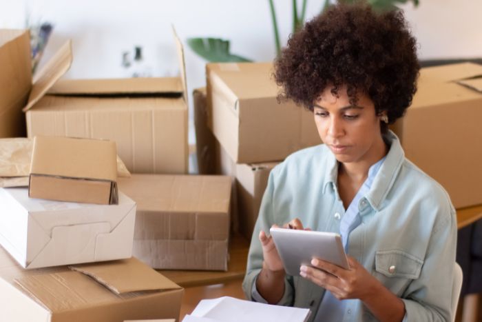 Mulher organizando caixas com tablet na mão