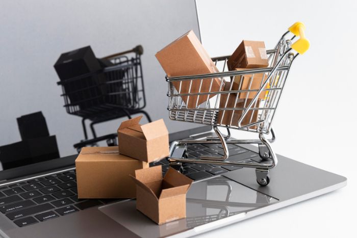 Carrinho de compras com encomenda em cima de um notebook.